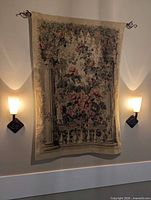 Full tapestry hanging on wall between sconces