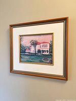 Framed painting hung on wall, full view shows frame, mat and artwork