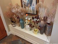 All items on white bench showing vases, planters and dried botanicals