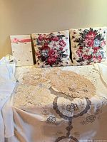 overview of linens and two floral needlepoint pillows on table