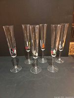 Full set of six clear glass champagne flutes standing upright