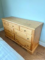 Front and right side view of pine dresser showing seven drawers and finish