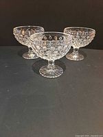 Front view of three clear hobnail dessert coupes on pedestal bases