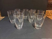 Front view of nine clear glass tumblers upright