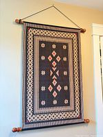 Full view of tapestry hanging on wall showing overall design and dowels