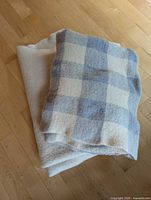 Both wool throws folded; plaid on top, solid cream beneath
