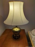 Full view of brass lamp with shade on table