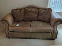 Front view of Concordian Chesterfield loveseat showing cushions, leather trim, nailhead detail