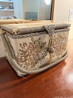 closed sewing basket front view showing tapestry panel and rope handle