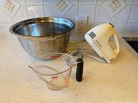 Hand mixer, bowl and measuring cup grouped on countertop