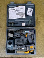 Open case showing drill, batteries, charger, bits, manual