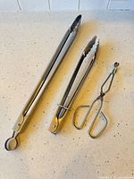 Three stainless tongs in varying styles and sizes