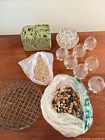 overview of entire lot showing foam brick, eight glass spheres, bag of marbles, bag of pebbles, metal grid