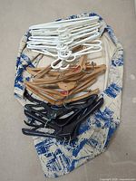 Group of white plastic, wood, and black plastic hangers laid out together