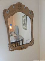 Front view of ornate painted wood wall mirror hanging on wall