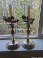 pair of silver-plated candlesticks with floral rings and tapers