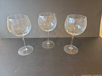 Three clear balloon red wine glasses upright on surface