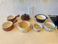 All seven mixed ceramic and porcelain ramekins displayed on countertop