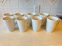 Front view of all eight white porcelain mugs