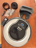 All items laid out: robot vacuum, charging dock, remote, boundary strip rolls, connectors, cleaning tool