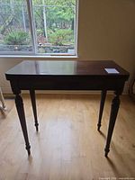 Full front view of mahogany side table by window