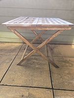 Side view of folded-leg wooden patio table on patio slab