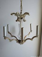 Full view of chandelier showing six glass arms, central column, candle sleeves