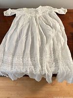 Full view of white christening gown laid flat