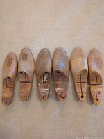 Six wooden shoe lasts lined up showing top view, details of vents and joints visible