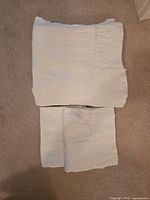 Folded white flannel sheet and pillowcases shown on carpet