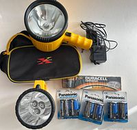 All lot items laid out: spotlight, charger, case, Duracell 9V pack, three Panasonic 2-D packs