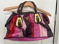 Front view of Prada striped patent leather handbag hanging