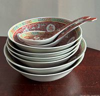 Stack of six bowls with longevity pattern and two matching soup spoons