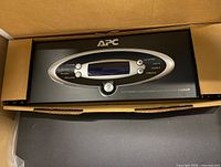 Front view of APC unit showing LCD and controls inside shipping box