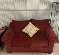 Front view of dark orange loveseat sofa with striped pillow