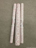 three rolls of vinyl wallpaper on floor