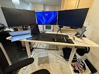 Complete workstation showing standing desk with monitors, laptop dock, keyboard, mouse, cable management trays and surge protector