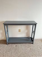 Front view of gray console table showing top, side panel design and lower shelf
