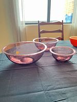 Three purple-pink transparent glass bowls