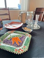 All items displayed on table: square carrot platter, red-amber leaf bowl, beer stein, clamp-top jar, small glass pitcher, candlestick