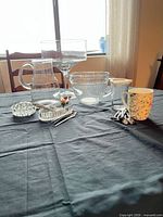 Full lot on table showing major glass pieces, crystal dishes, mug and utensils