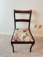 Front view of wooden dining chair showing floral upholstered seat and overall form