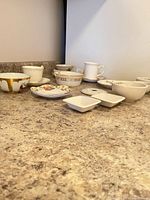 Group shot of assorted porcelain teacups, saucers, bowls and prep dishes on countertop