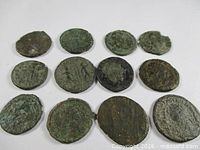 Group of 12 Roman coins with green patina displayed on white background