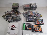 Full lot showing three stacks of game cases, spread of PS1 and PC titles, Guild Wars 2 box, Resident Evil, MDK, Legend of Dragoon in foreground