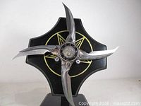 Front view of assembled shuriken on stand showing blades and emblem