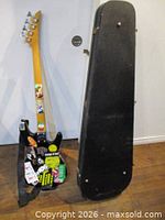 Full view of bass guitar back with stickers and hard case standing upright