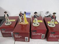 Four Nelson figures standing on respective red Britains boxes