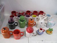 Group of assorted colourful ceramic mugs, some with sculpted lids, arranged on tabletop