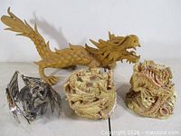 Group shot of four dragon items: metal dragon, handmade tan dragon, two keepsake boxes
